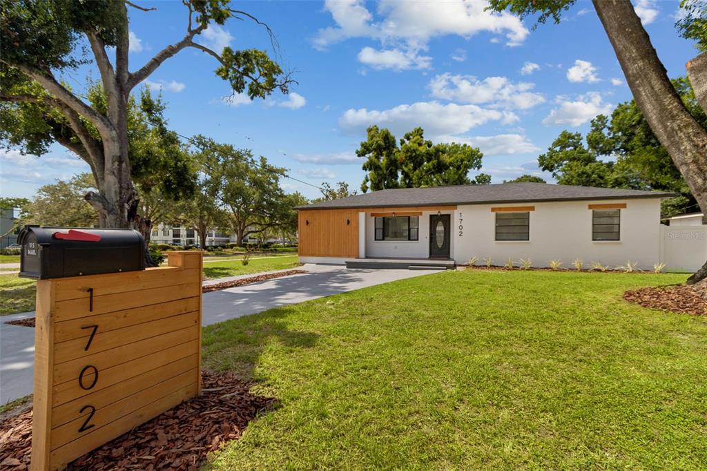 An open-concept kitchen and living area featuring white cabinets, a kitchen island, and wood flooring — 1702 W JOHNSTON AVENUE, TAMPA, FL