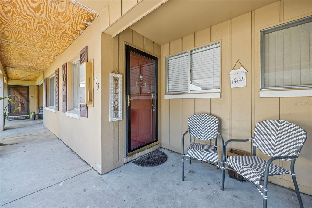 A covered concrete walkway leads to the front entrance of a unit with two chairs — 1008 APOLLO BEACH BOULEVARD UNIT 103, APOLLO BEACH, FL