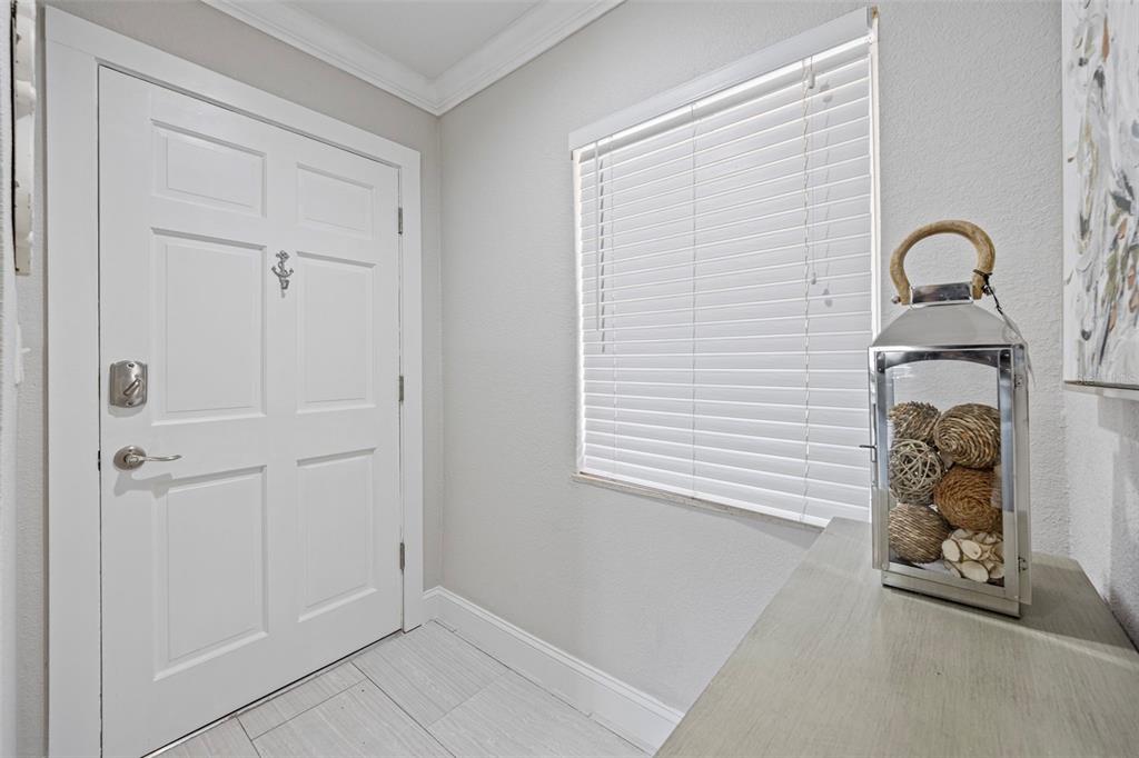An entryway features a white door, a window with blinds, and a decorative lantern on a table — 1008 APOLLO BEACH BOULEVARD UNIT 103, APOLLO BEACH, FL