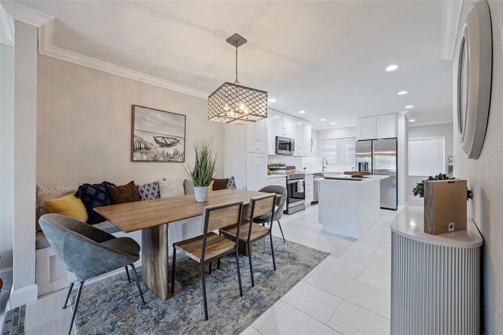 A dining area with a built-in bench, wooden table, and chairs adjacent to a kitchen — 1008 APOLLO BEACH BOULEVARD UNIT 103, APOLLO BEACH, FL