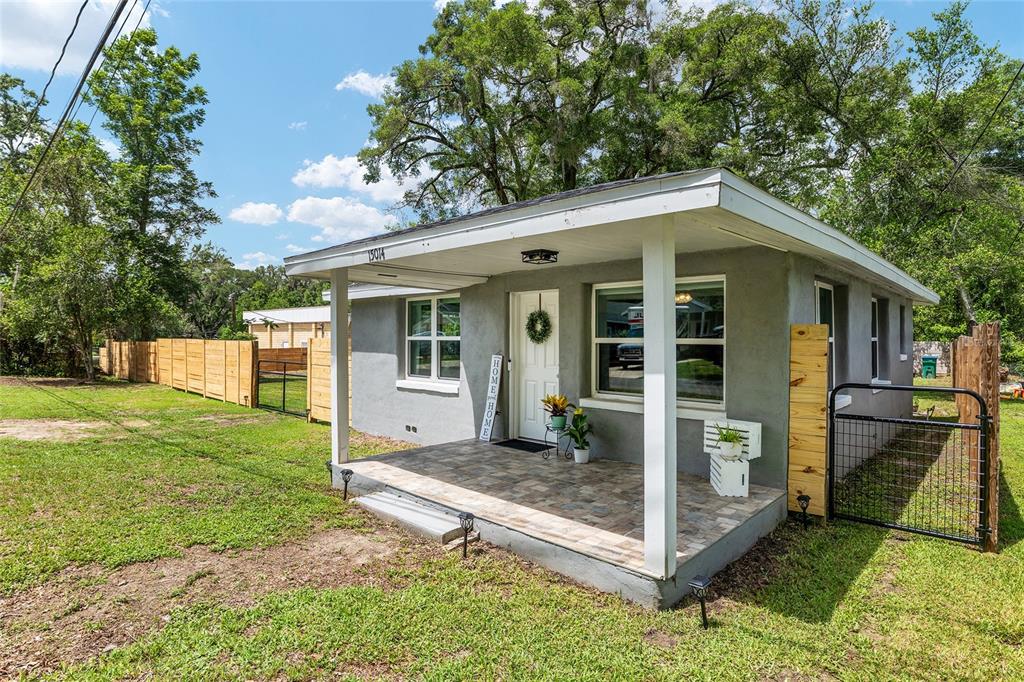 A gray house with a covered front porch, tiled floor, and a wooden fence — 15014 NW 135TH TERRACE, ALACHUA, FL