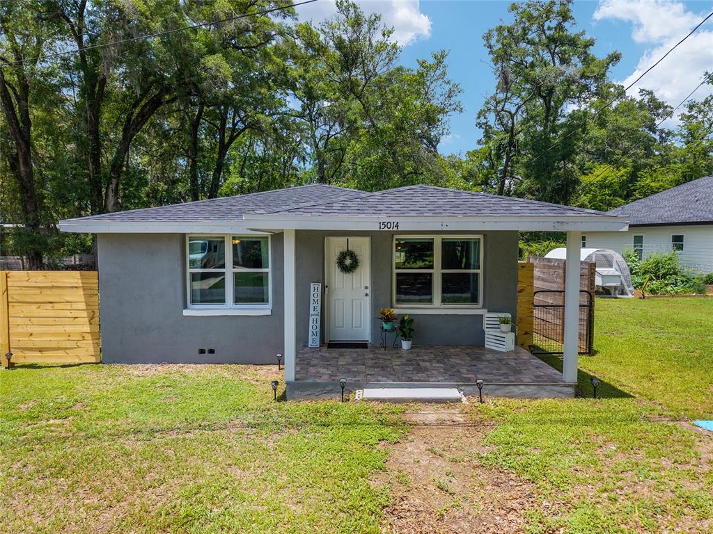 A gray single-story house features a covered front porch, a tiled floor, and wood fencing — 15014 NW 135TH TERRACE, ALACHUA, FL