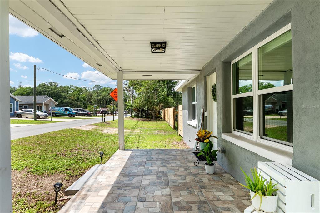 A covered porch with tiled flooring overlooks a residential street and a grassy yard — 15014 NW 135TH TERRACE, ALACHUA, FL