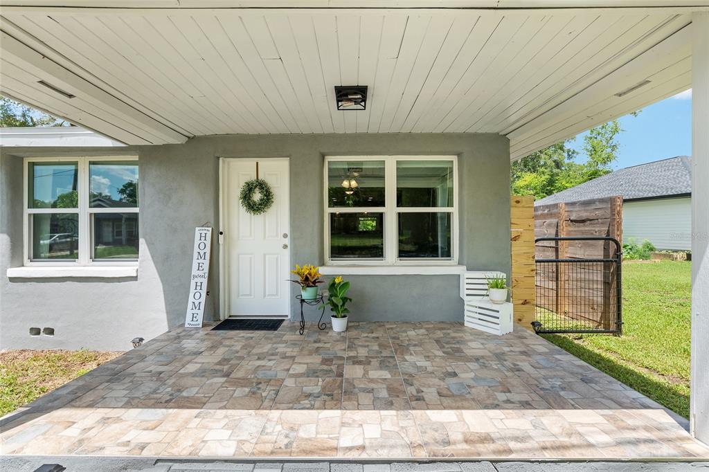 A covered front porch features tiled flooring, a white front door, and two windows — 15014 NW 135TH TERRACE, ALACHUA, FL