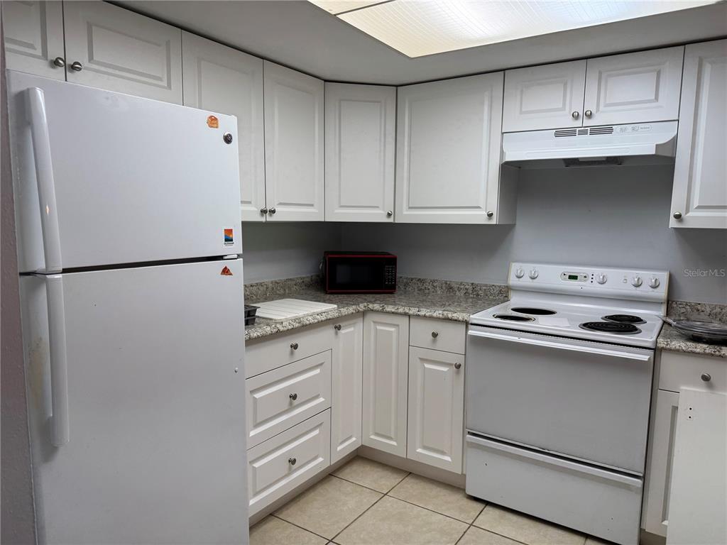 A kitchen with white cabinets, white appliances, and speckled countertops — 11616 BAYWOOD MEADOWS DRIVE UNIT 2, NEW PORT RICHEY, FL