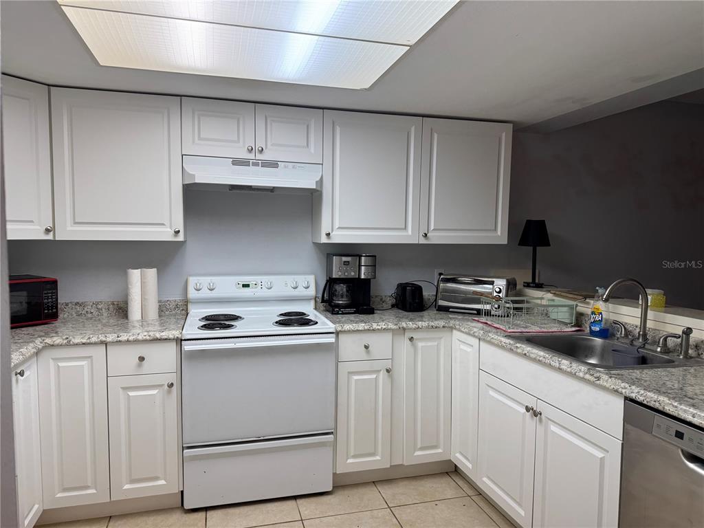 A kitchen with white cabinets, granite countertops, a white stove, and a stainless steel dishwasher — 11616 BAYWOOD MEADOWS DRIVE UNIT 2, NEW PORT RICHEY, FL