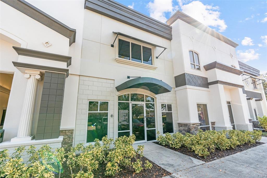 The exterior of a two-story commercial building features a glass entrance with a green awning — 8865 COMMODITY CIRCLE UNIT 14, ORLANDO, FL