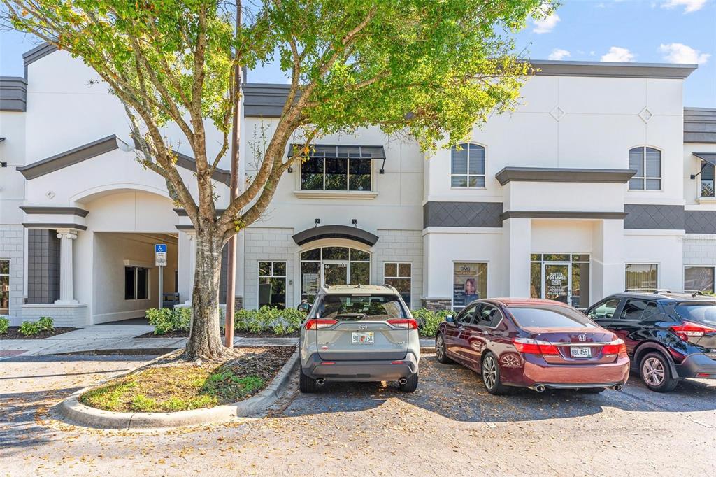 A two-story commercial building exterior with parked cars and a tree in the foreground — 8865 COMMODITY CIRCLE UNIT 14, ORLANDO, FL