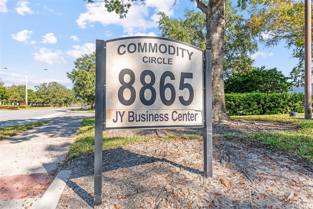 A sign for a business center stands on a grassy area beside a paved road — 8865 COMMODITY CIRCLE UNIT 14, ORLANDO, FL