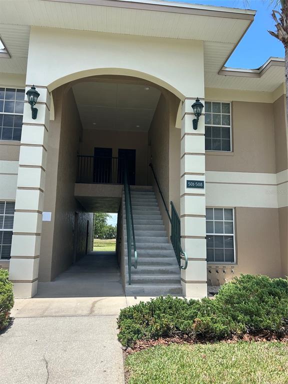 An exterior view of a two-story apartment building entrance with stairs leading to upper units — 508 EAGLE POND DRIVE UNIT 508, WINTER HAVEN, FL
