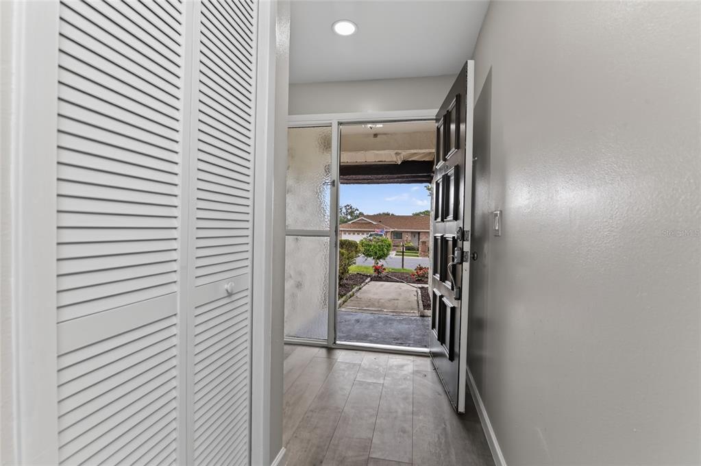 An entryway with light wood-look flooring, a louvered closet door, and an open front door — 3179 FOXWOOD DR, APOPKA, FL