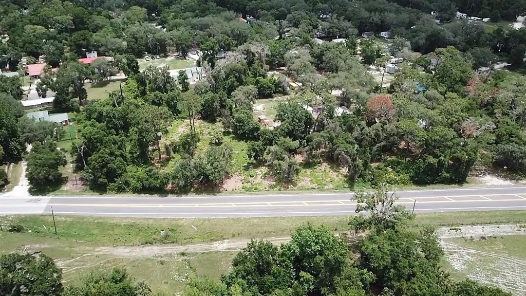 An aerial view shows a wooded lot bordering a paved road with surrounding residential properties — COUNTY ROAD 42, UMATILLA, FL