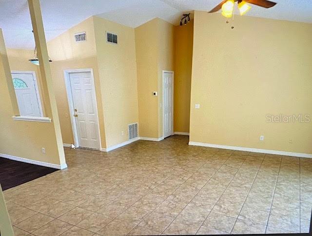 A living area with light yellow walls, tile flooring, and a vaulted ceiling — 40107 OAKRIDGE DRIVE, LADY LAKE, FL