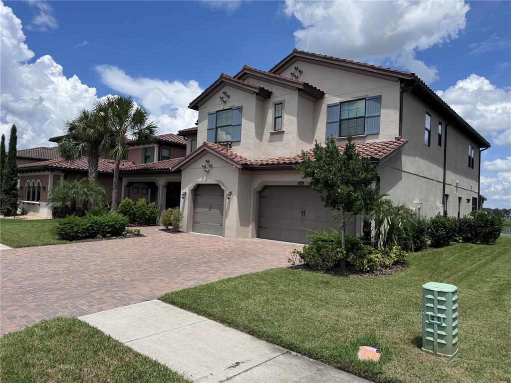 A two-story stucco house with a tile roof, three-car garage, and a paved driveway — 28661 PICANA LANE, WESLEY CHAPEL, FL