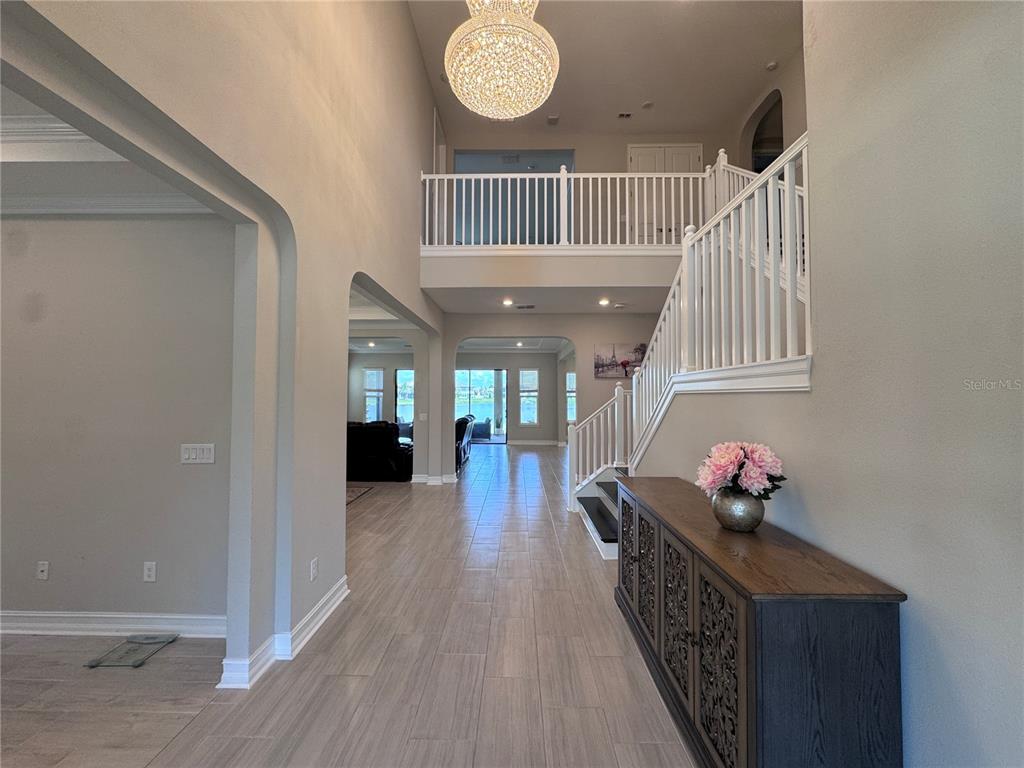 A foyer with tile flooring leads to a staircase, a loft, and a living area — 28661 PICANA LANE, WESLEY CHAPEL, FL