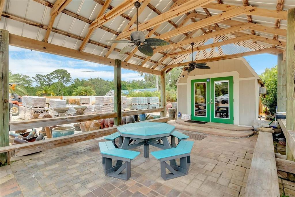 A covered outdoor patio features a hexagonal picnic table, ceiling fans, and a small building — 8440 COUNTY ROAD 48, YALAHA, FL