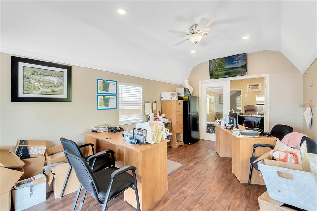 An office space features two wooden desks, black chairs, a refrigerator, and wood-look flooring — 8440 COUNTY ROAD 48, YALAHA, FL