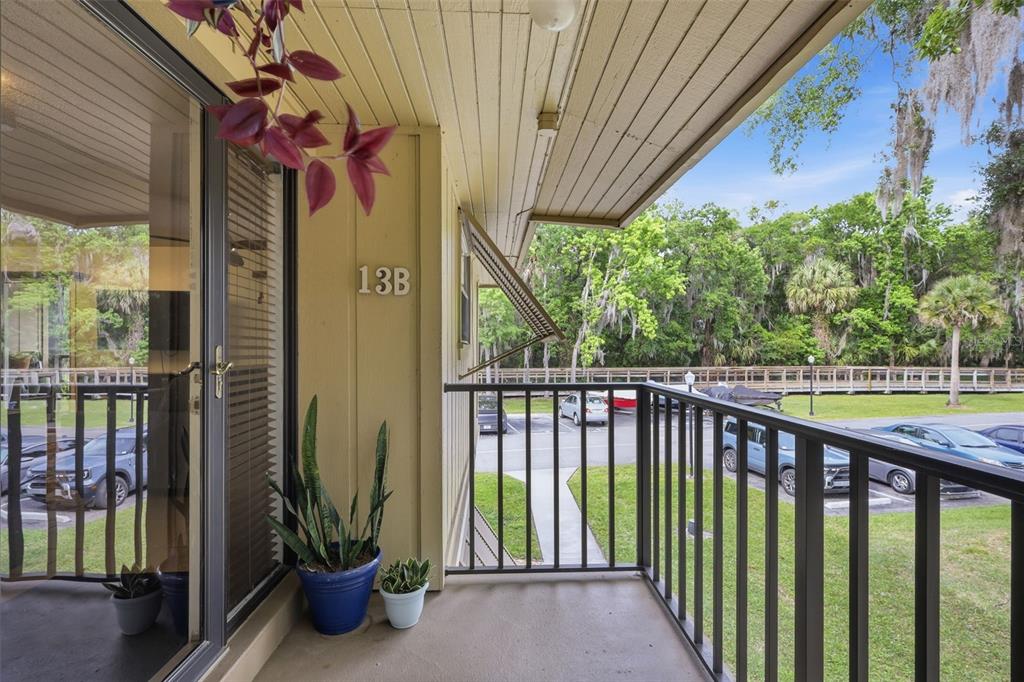 A balcony with a metal railing overlooks a parking lot and a wooded area — 140 ORCHID WOODS COURT UNIT 13B, DELTONA, FL