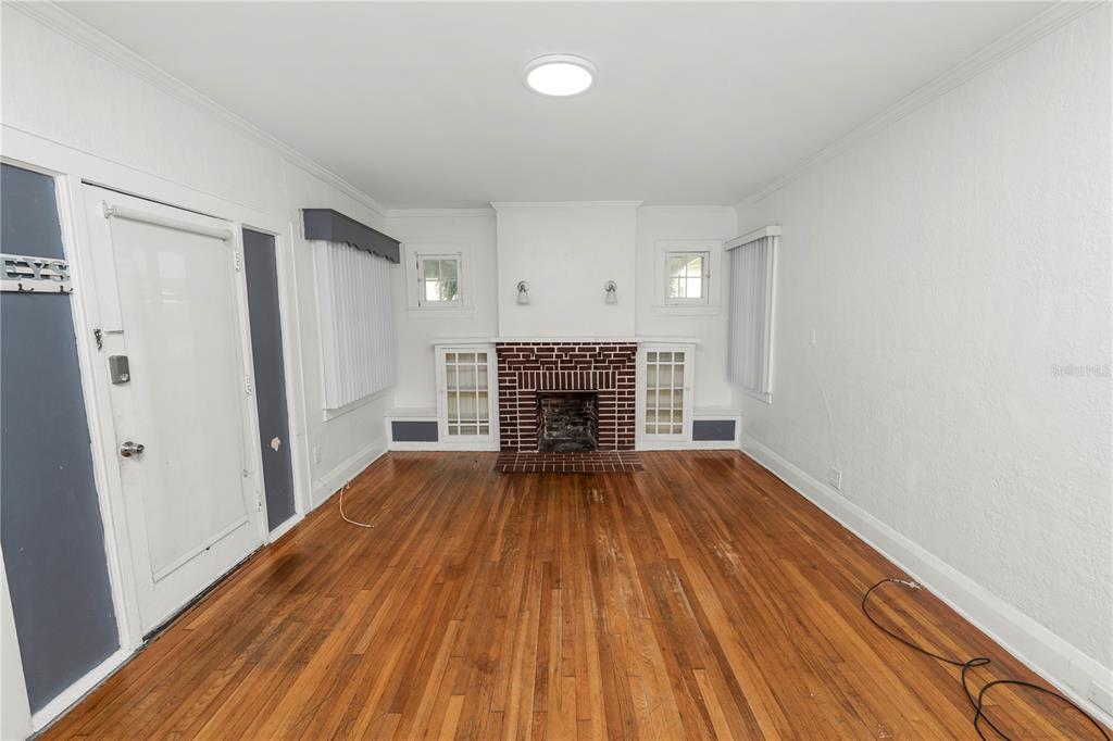 A living room features hardwood floors, a brick fireplace, built-in cabinets, and white walls — 1220 RUBY STREET, LAKELAND, FL