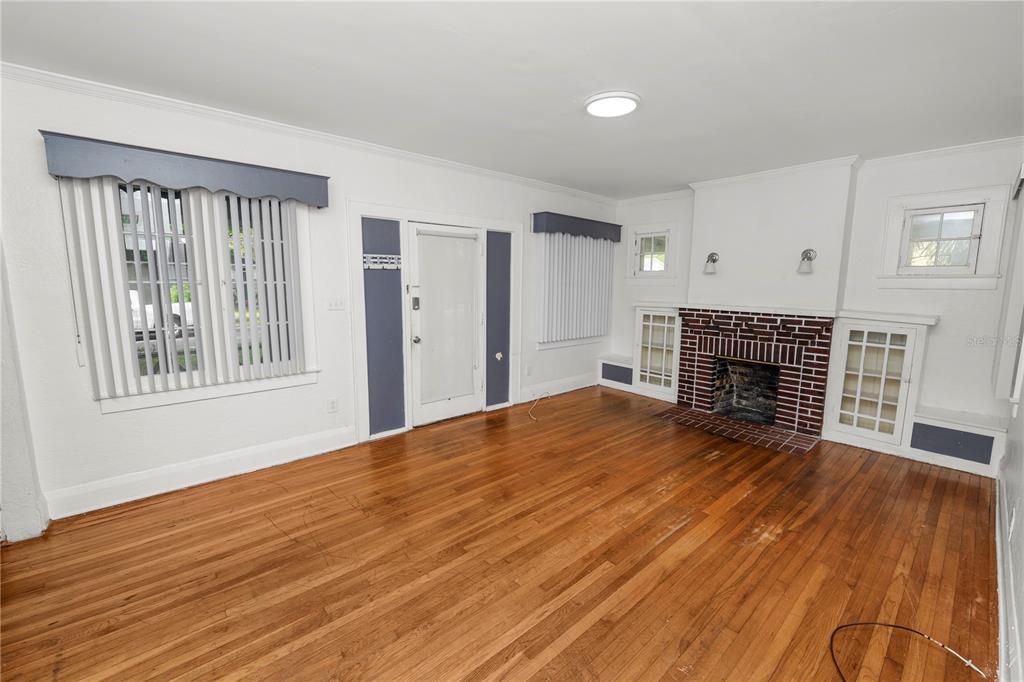 A living room features hardwood floors, a brick fireplace, built-in shelving, and white walls — 1220 RUBY STREET, LAKELAND, FL