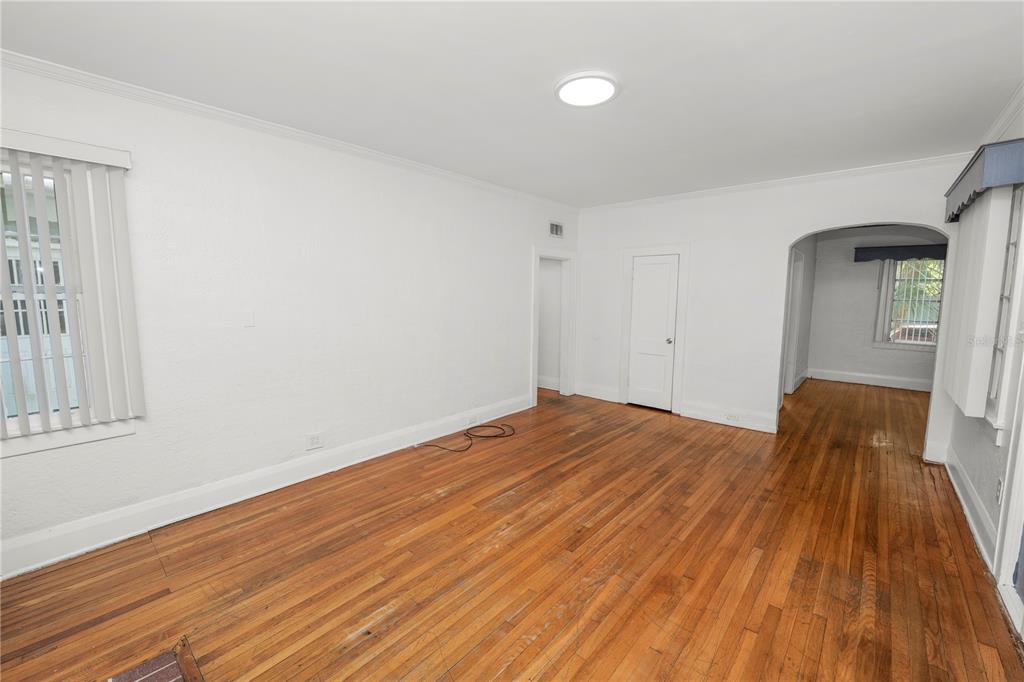 An empty room with white walls, hardwood floors, and an arched doorway leading to another room — 1220 RUBY STREET, LAKELAND, FL