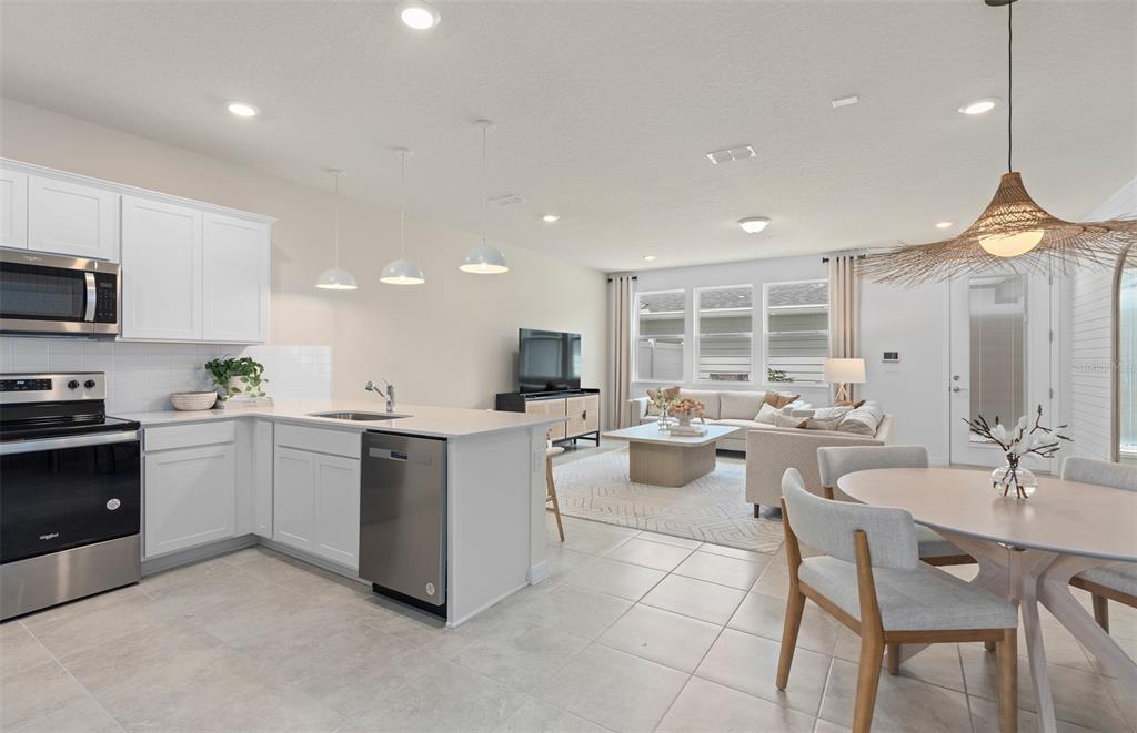 An open-concept kitchen, dining area, and living room featuring white cabinets and tile flooring — 15516 PEACEFUL PINES ALLEY, CLERMONT, FL
