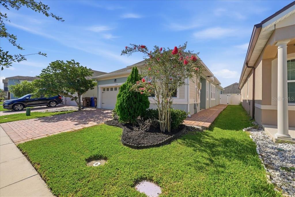 A single-story house with a brick driveway, a small front garden, and a blue car — 2524 RAPOLLO DRIVE, KISSIMMEE, FL