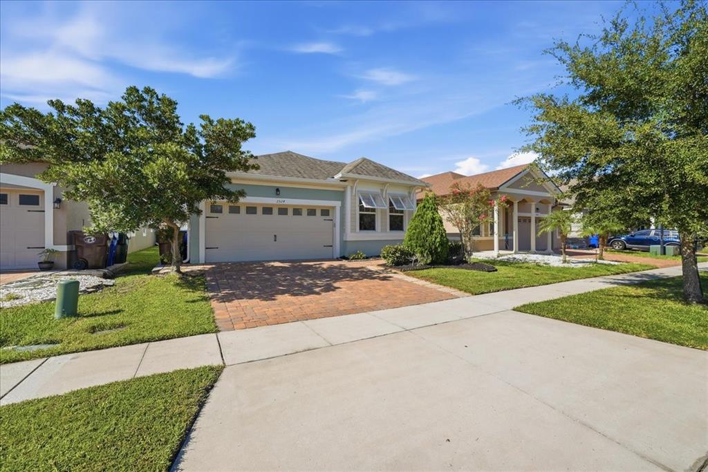 A single-story house with a light green exterior, a two-car garage, and a brick driveway — 2524 RAPOLLO DRIVE, KISSIMMEE, FL