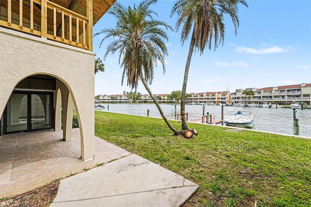 A living room with wood-look tile floors, a wood-paneled ceiling, and sliding glass doors — 546 PLAZA SEVILLE COURT UNIT 85, TREASURE ISLAND, FL
