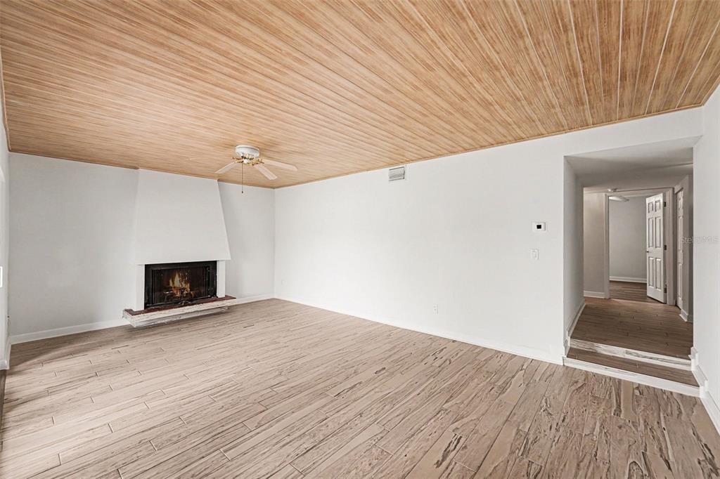 A living room features a fireplace, wood-look tile flooring, and a wood-paneled ceiling — 546 PLAZA SEVILLE COURT UNIT 85, TREASURE ISLAND, FL