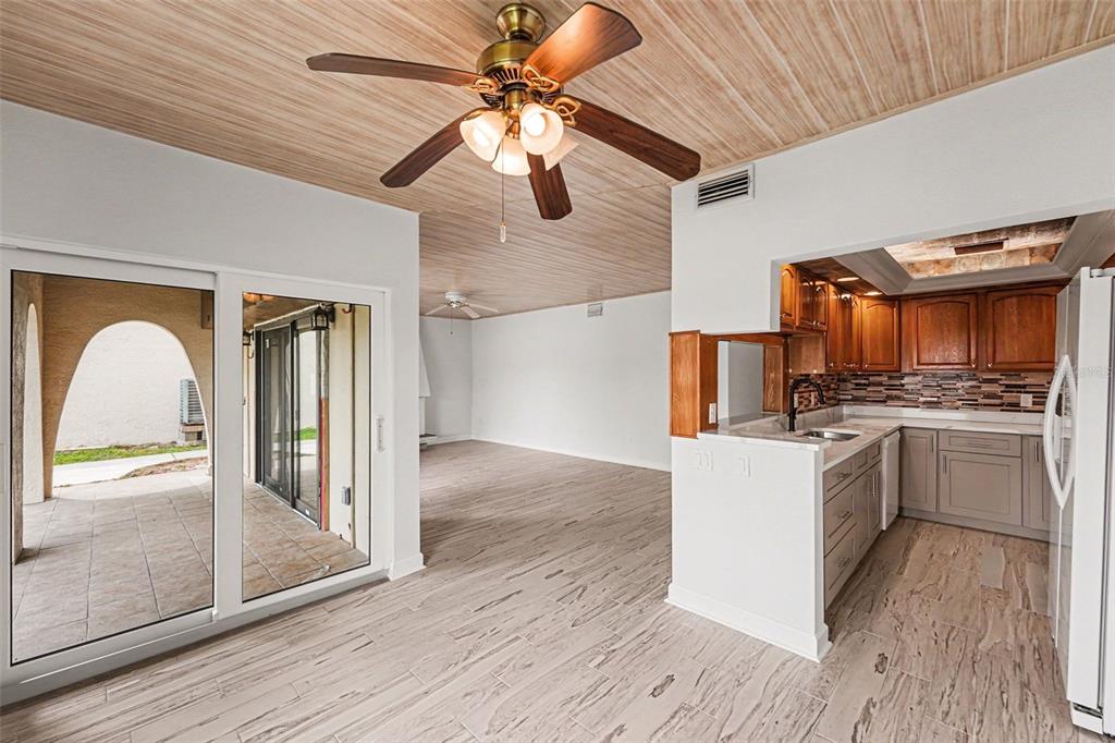 A view of a kitchen with wood cabinets and a living area with wood-paneled ceilings — 546 PLAZA SEVILLE COURT UNIT 85, TREASURE ISLAND, FL