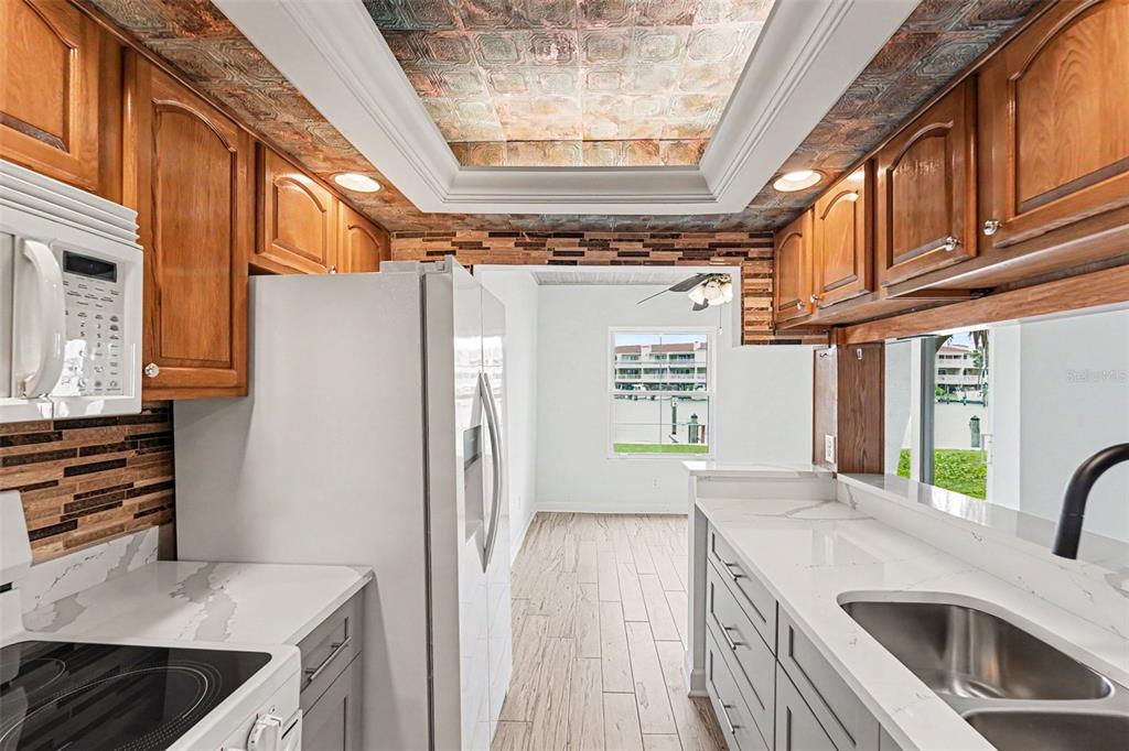 A kitchen with wood cabinets, gray lower cabinets, white countertops, and a copper-tiled ceiling — 546 PLAZA SEVILLE COURT UNIT 85, TREASURE ISLAND, FL