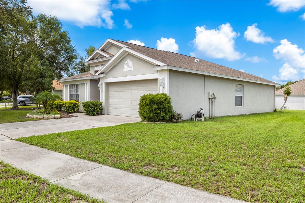 A single-story house with a beige stucco exterior, a two-car garage, and a grassy lawn — 10234 HUNTERS HAVEN BOULEVARD, RIVERVIEW, FL