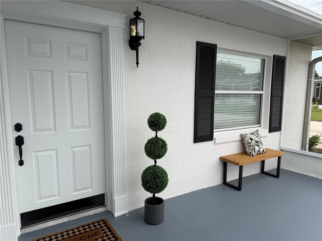A white front door with black hardware sits beside a window with black shutters — 2947 TANGERINE COURT, LEESBURG, FL