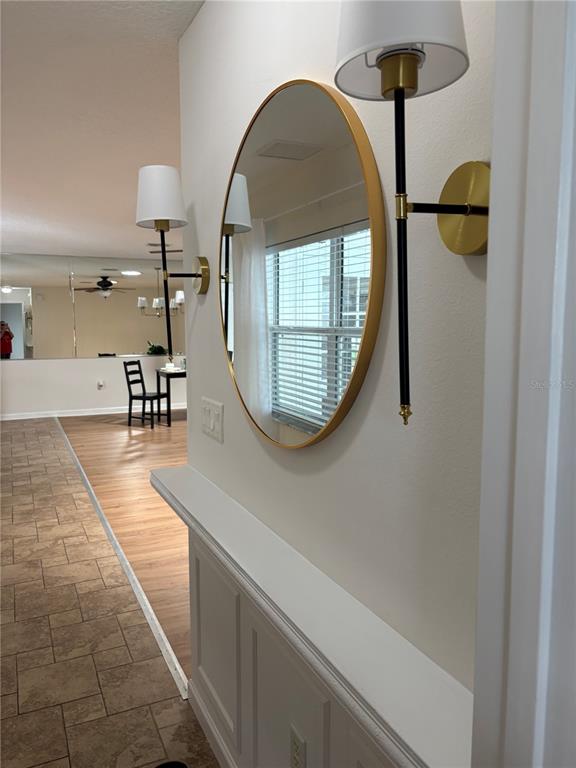 A hallway features a white wainscoted ledge, a round gold-framed mirror, and two wall sconces — 2947 TANGERINE COURT, LEESBURG, FL