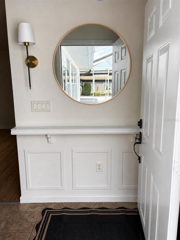 An entryway features a round gold-framed mirror, a wall sconce, and a white console shelf — 2947 TANGERINE COURT, LEESBURG, FL