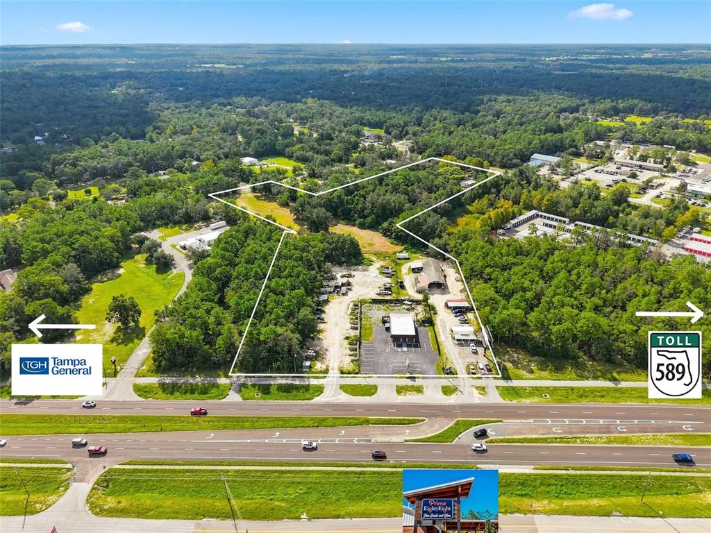 This aerial view shows a commercial property with a parking lot and buildings near a highway — 15440 CORTEZ BOULEVARD, BROOKSVILLE, FL