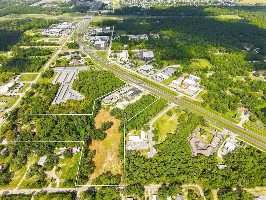 An aerial view shows a large, partially wooded plot of land outlined in white — 15440 CORTEZ BOULEVARD, BROOKSVILLE, FL