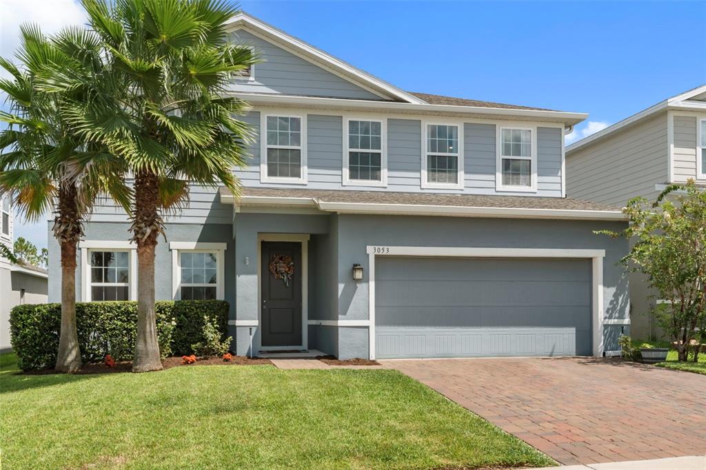 A two-story house with light blue siding, a two-car garage, and palm trees in front — 3053 HILL POINT STREET, MINNEOLA, FL