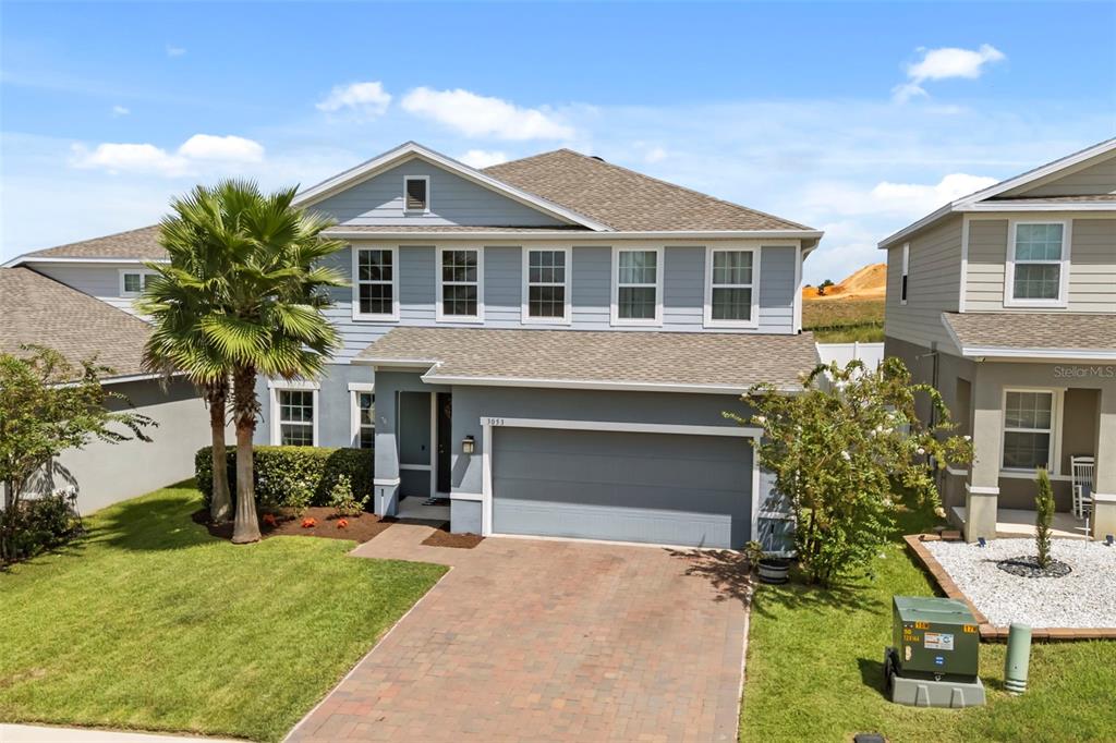 A two-story light blue house with a paved driveway and a palm tree in front — 3053 HILL POINT STREET, MINNEOLA, FL