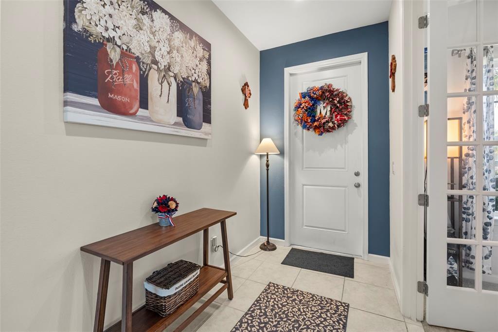 An entryway features a console table, a blue accent wall with a door, and artwork — 3053 HILL POINT STREET, MINNEOLA, FL