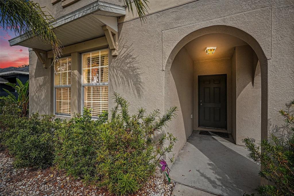A beige stucco house exterior features an arched entryway, a dark door, and two windows — 10657 STANDING STONE DR, WIMAUMA, FL