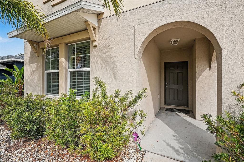 A beige stucco house exterior features a covered arched entryway and a dark front door — 10657 STANDING STONE DR, WIMAUMA, FL
