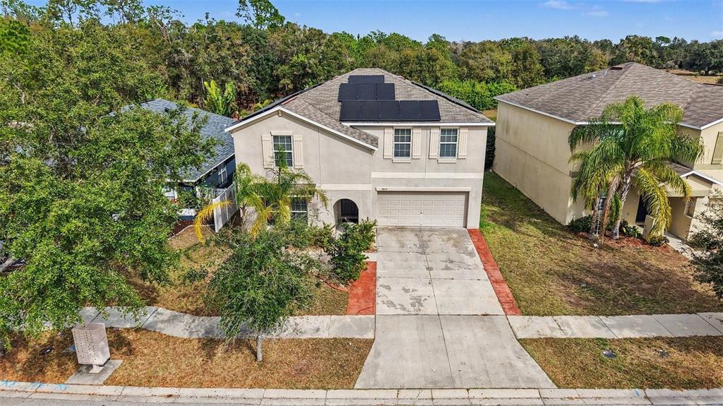 An aerial view of a two-story suburban house with solar panels on the roof — 10657 STANDING STONE DR, WIMAUMA, FL