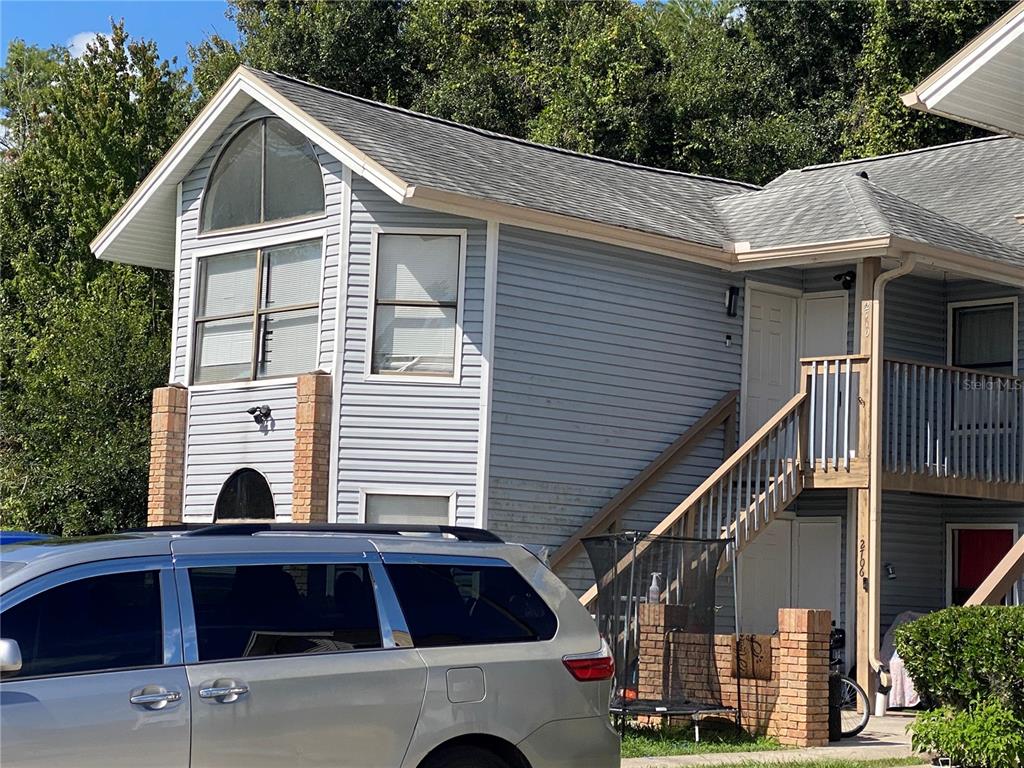A blue pickup truck is parked between two cars in front of a multi-story building — 2706 RIO GRANDE TRAIL UNIT 2706, KISSIMMEE, FL