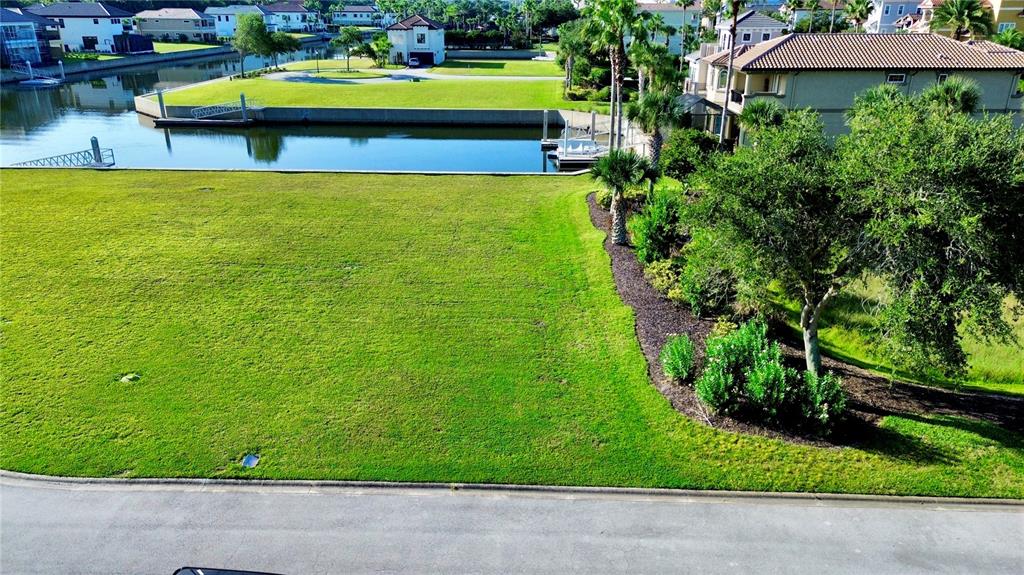 An aerial view shows a vacant grassy lot next to a canal and residential homes — 5 SCHOONER CIRCLE, PALM COAST, FL