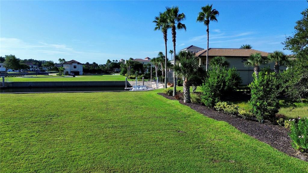 A grassy lawn overlooks a canal with palm trees and houses in the background — 5 SCHOONER CIRCLE, PALM COAST, FL