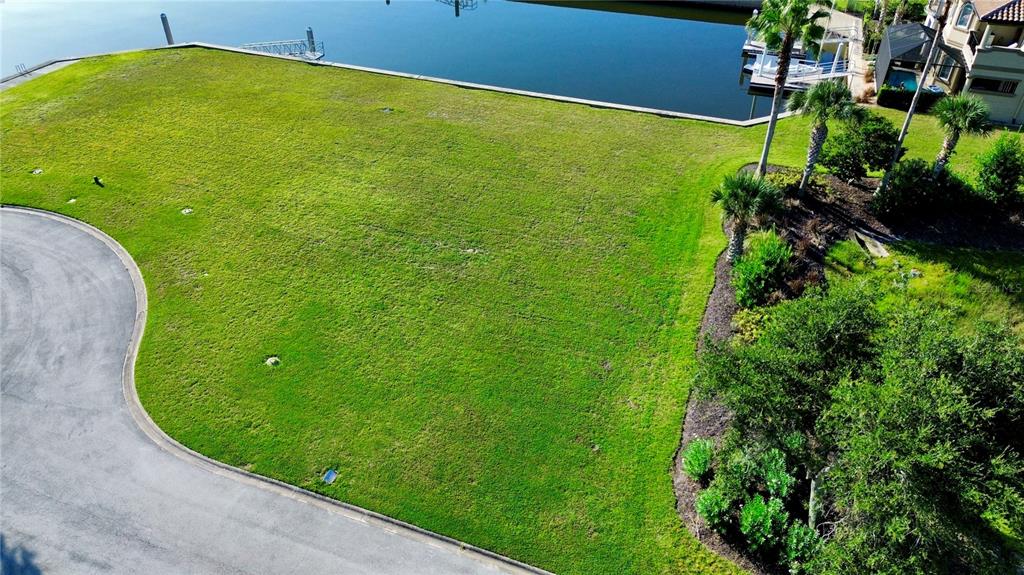 An aerial view shows a vacant, grassy residential lot bordering a canal and a paved road — 5 SCHOONER CIRCLE, PALM COAST, FL