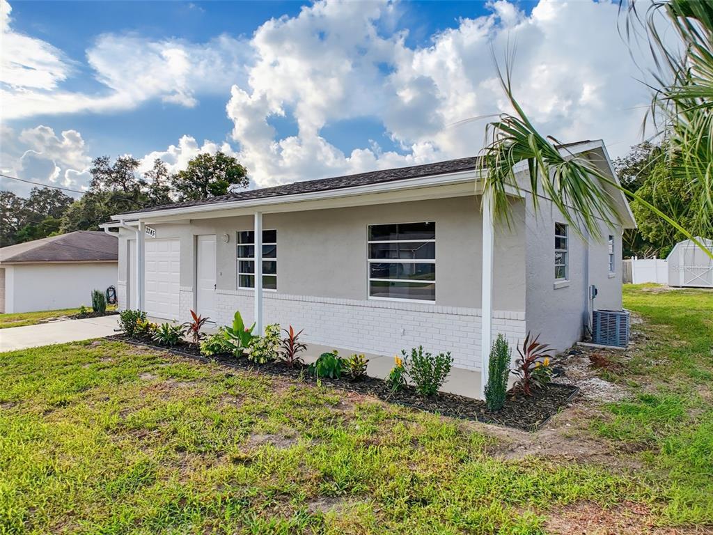 A single-story house with gray stucco walls, white brick accents, and a front-facing garage — 2245 BISHOP ROAD, SPRING HILL, FL