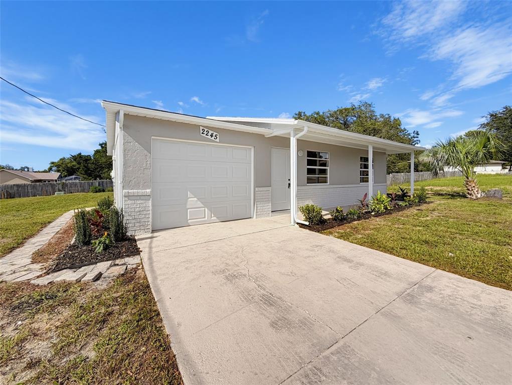A single-story house with a white garage, gray siding, and a concrete driveway — 2245 BISHOP ROAD, SPRING HILL, FL